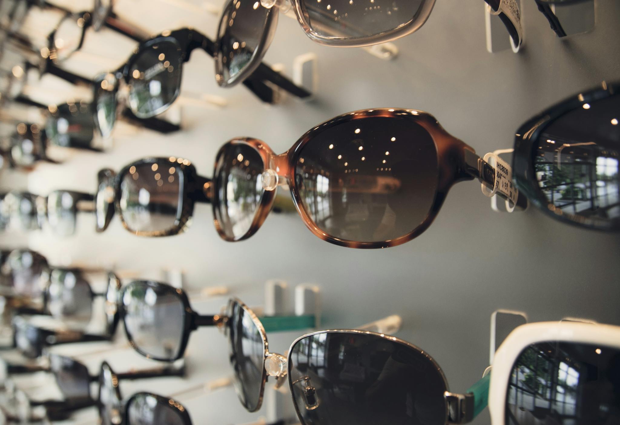 A variety of fashionable sunglasses on display in an optical store with soft lighting.